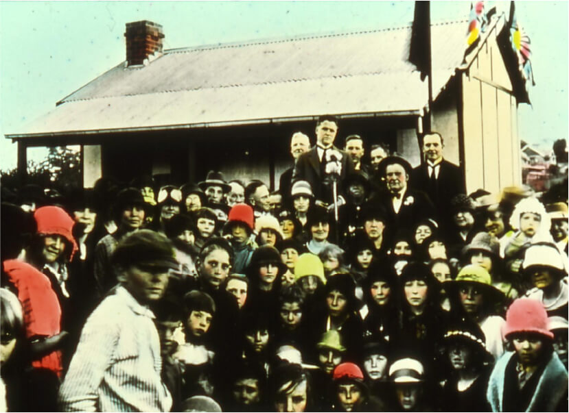 Lucy Willeri standing beside the Mayor at the Cottage Handover on 1 August 1925, holding a black kewpie doll.